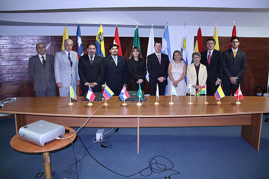Imagem dos participantes da reunião, em pé, à frente da mesa de debates do evento.